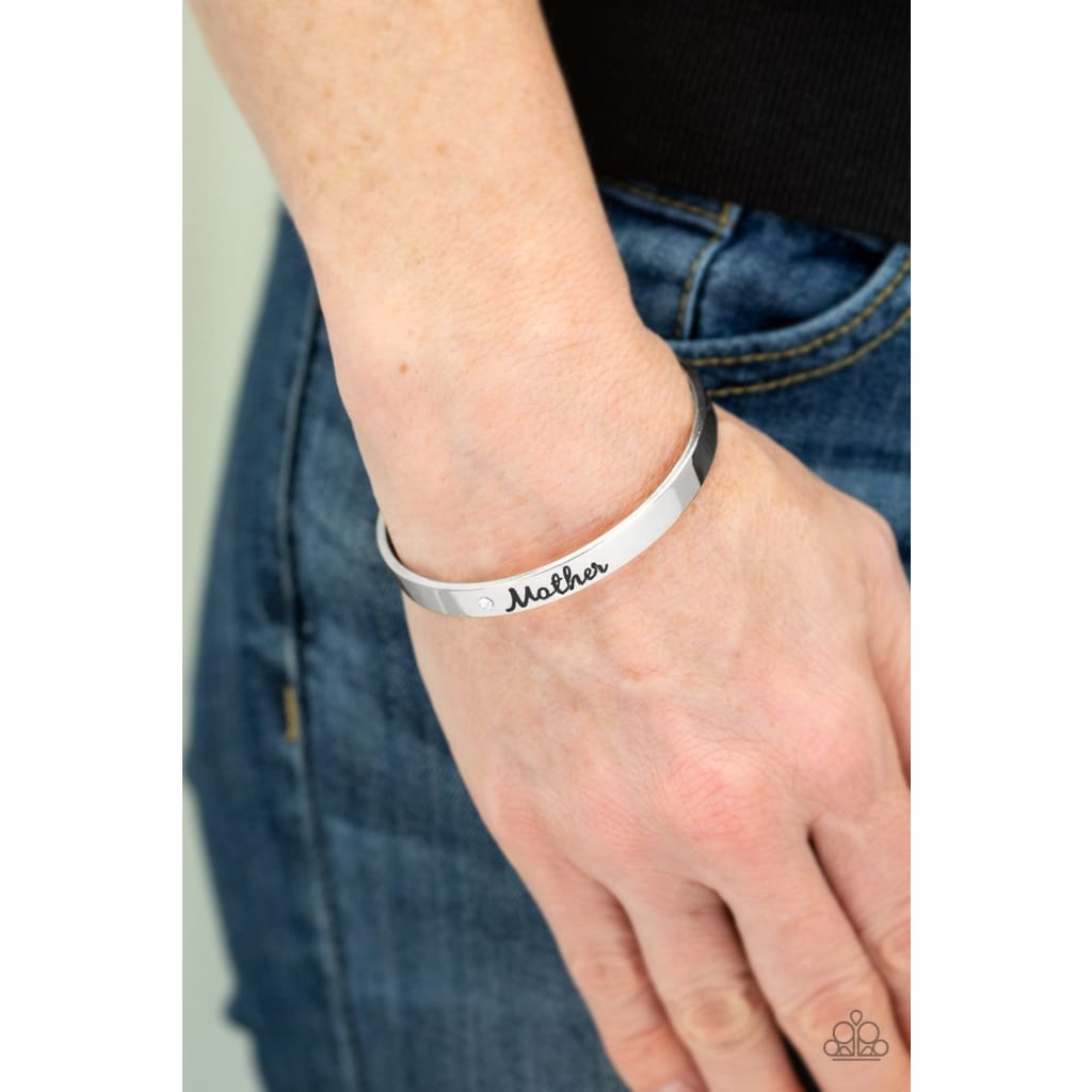 Paparazzi Every Day Is Mothers Day - Mom Bracelet Silver A sleek silver cuff wraps around the wrist in a casual fashion. Dotted with a dainty white rhinestone, the shimmery cuff is engraved in the word “Mother” for a loving finish. Sold as one individual cuff bracelet.